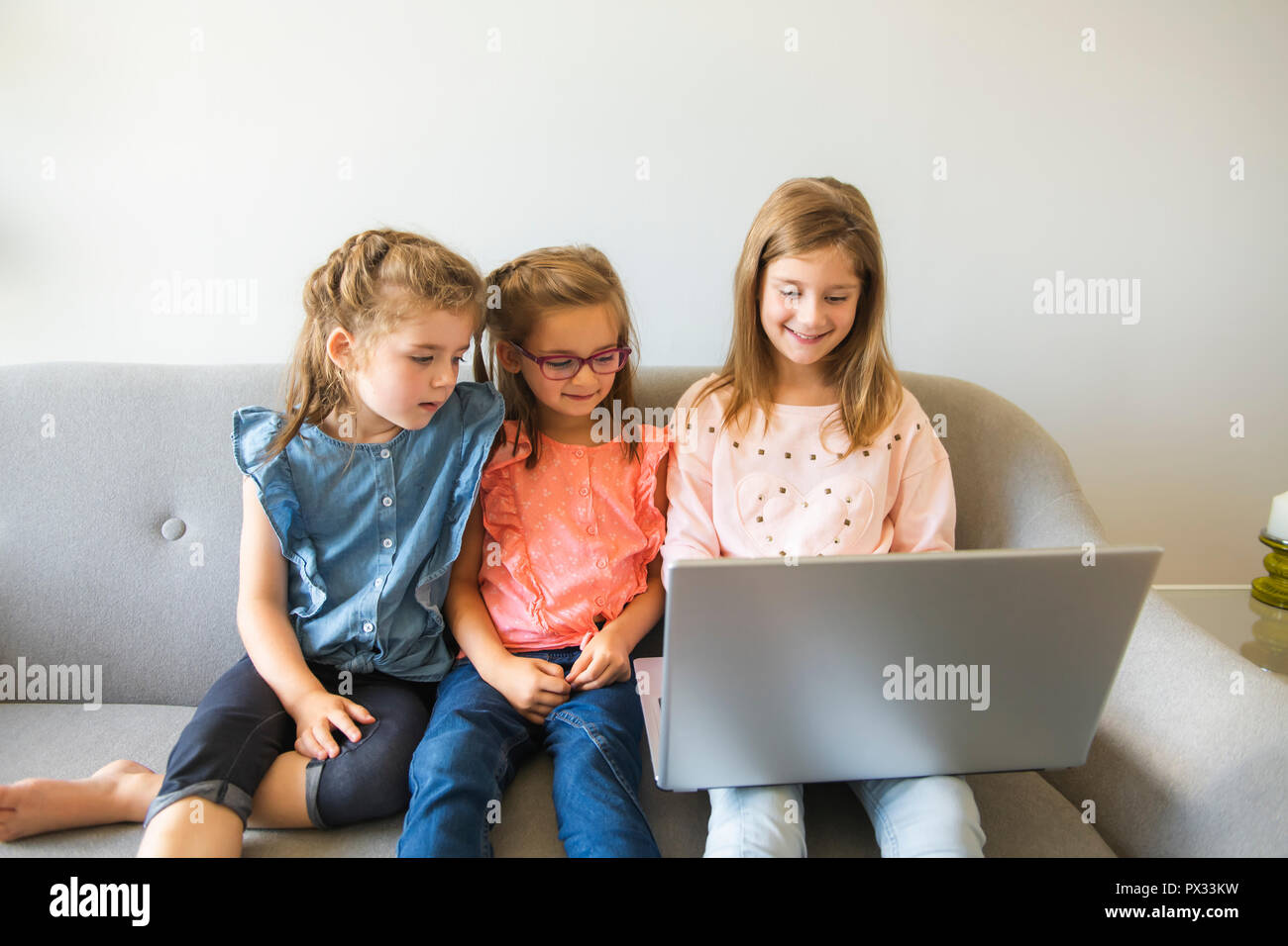 Three sisters girls sit on the sofa at home with laptop Stock Photo - Alamy