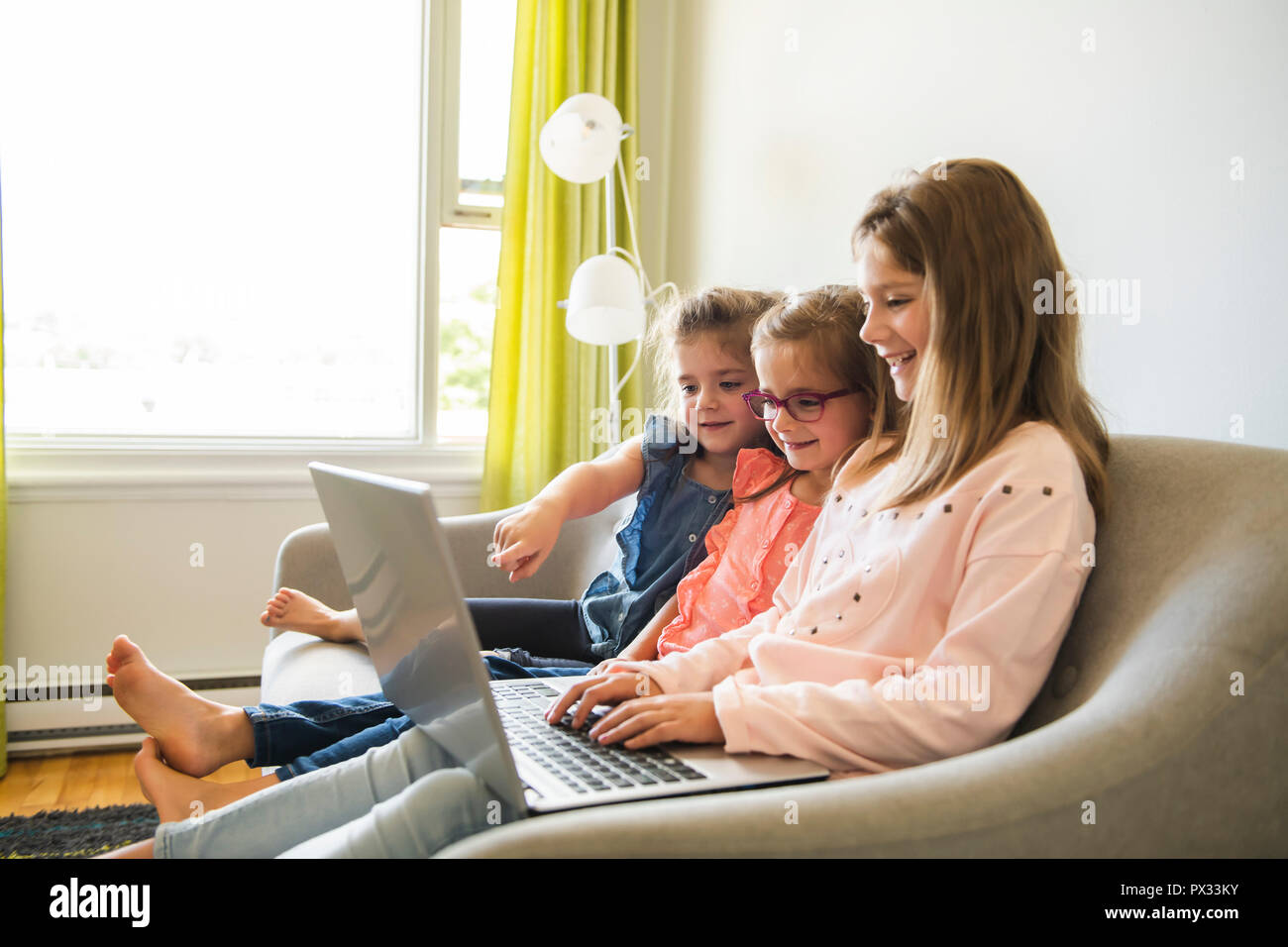 Three sisters girls sit on the sofa at home with laptop Stock Photo - Alamy