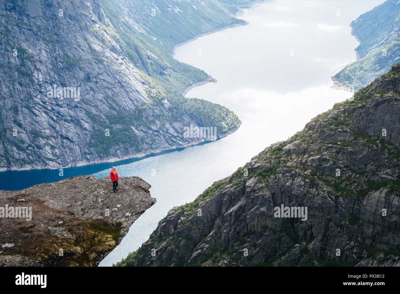 Trolltunga Hike. Girl tourist enjoys a beautiful view on Ringedalsvatnet lake. Summer Landscape with Mountain View Stock Photo