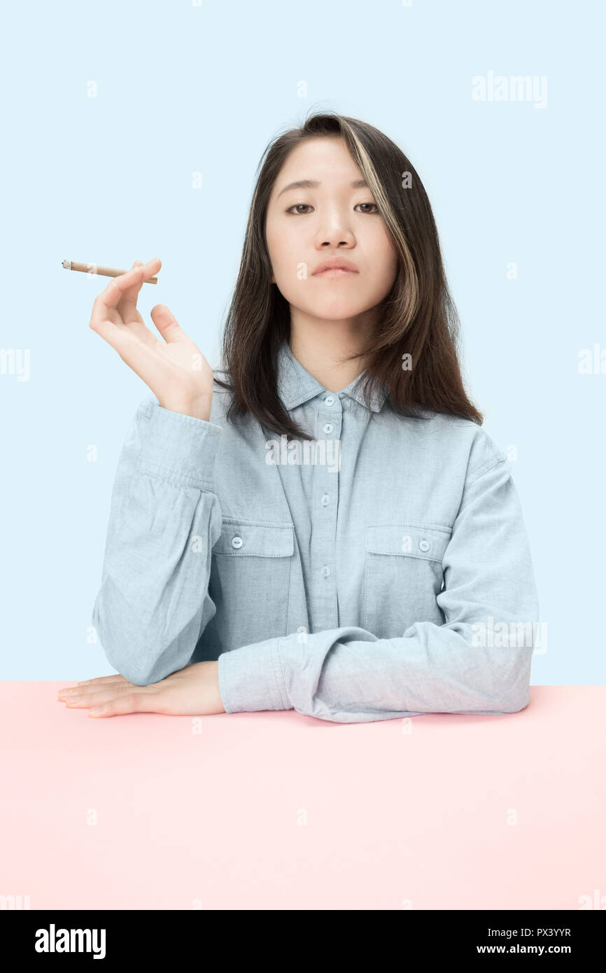 Handsome young korean women smoking cigar while sitting at table at