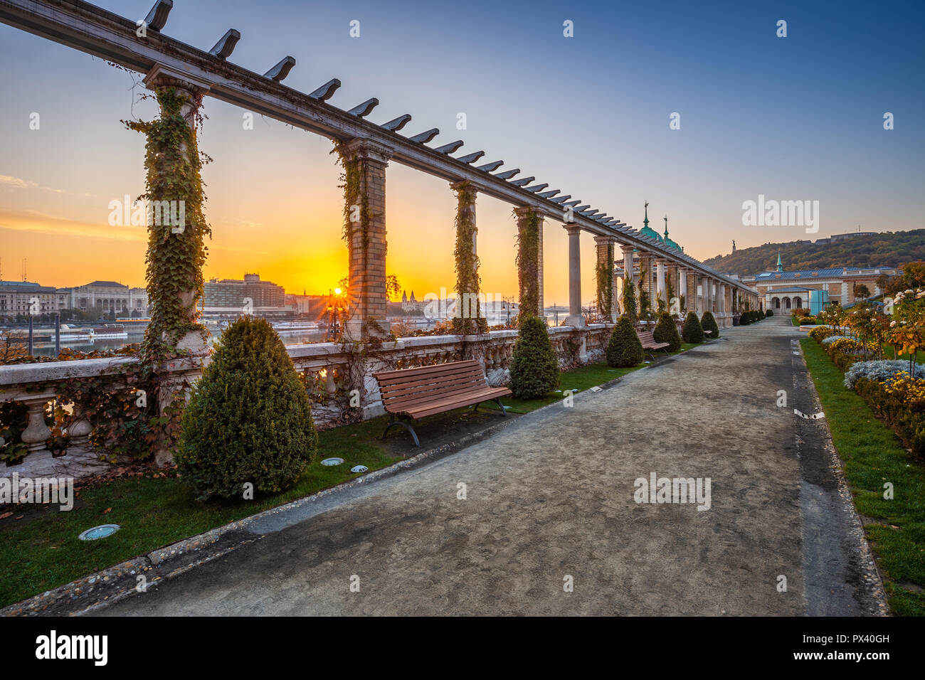 Budapest, Hungary - Beautiful sunrise at Varkert Bazaar with bench, Statue of Liberty at background and autumn foliage Stock Photo