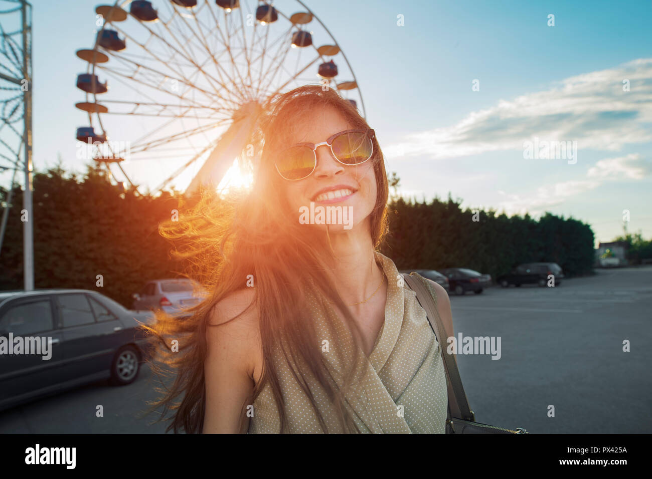 woman smiling cheerfully in front of a ferris wheel Stock Photo