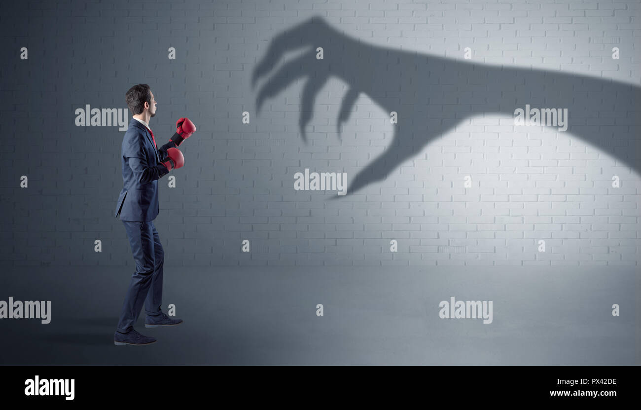 Tiny businessman fighting with scary hand shadow  Stock Photo