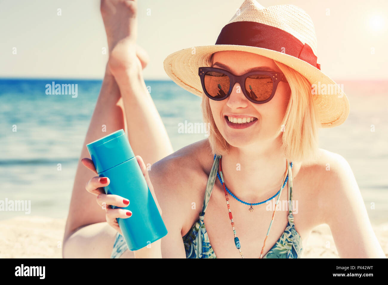 beautiful young woman holding a sun cream bottle on the beach Stock Photo