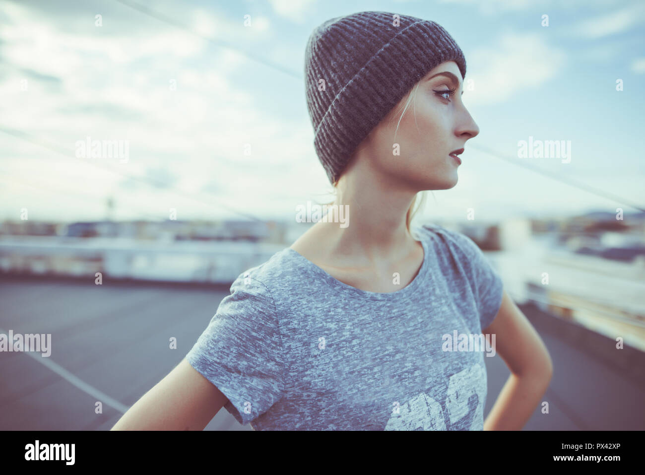 young woman is posing on a rooftop wearing street urban style outfit Stock Photo