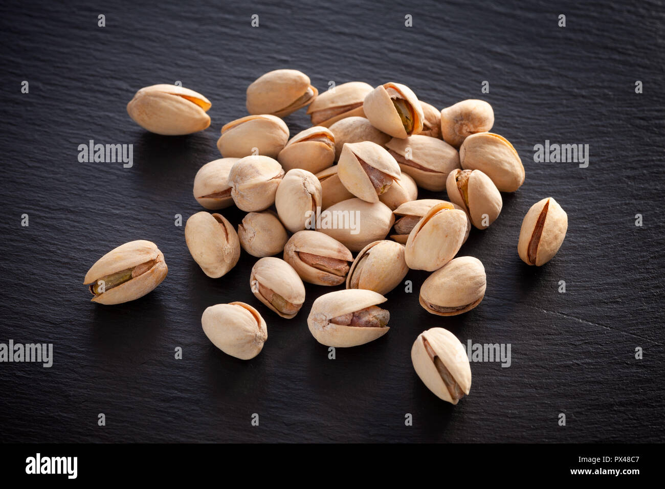 Salted pistachios on a black slate background. Close up. Stock Photo