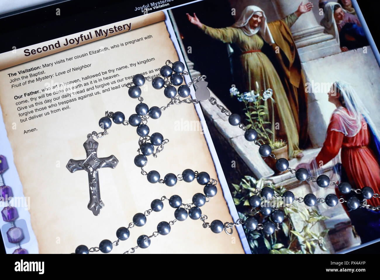 Christian Rosary on a digital tablet.  Catholic prayer. The Second Joyful Mystery : the Visitation. Stock Photo