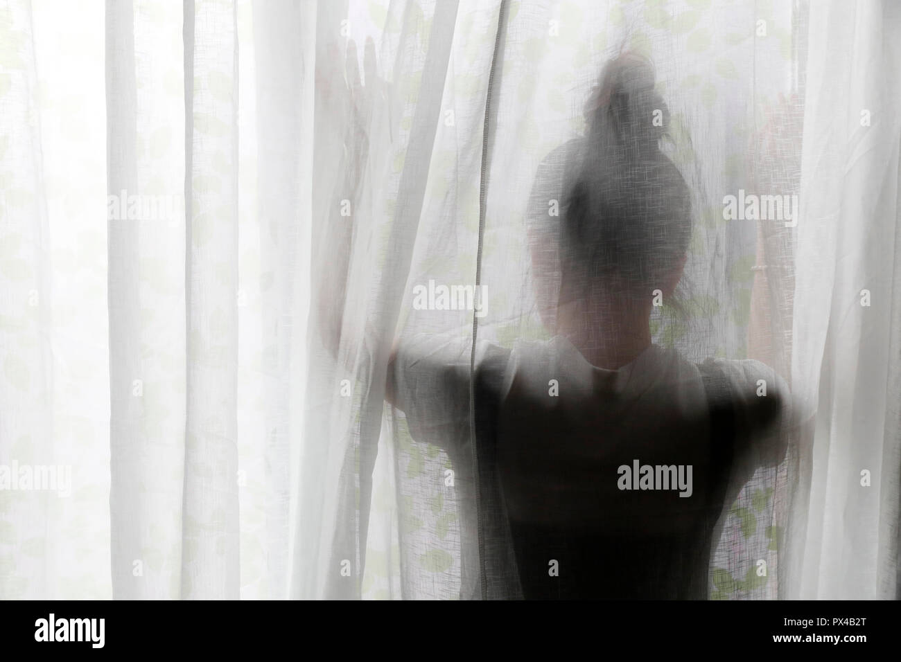 Silhouette of a woman behind a semi transparent curtain.  Ho Chi Minh City. Vietnam. Stock Photo