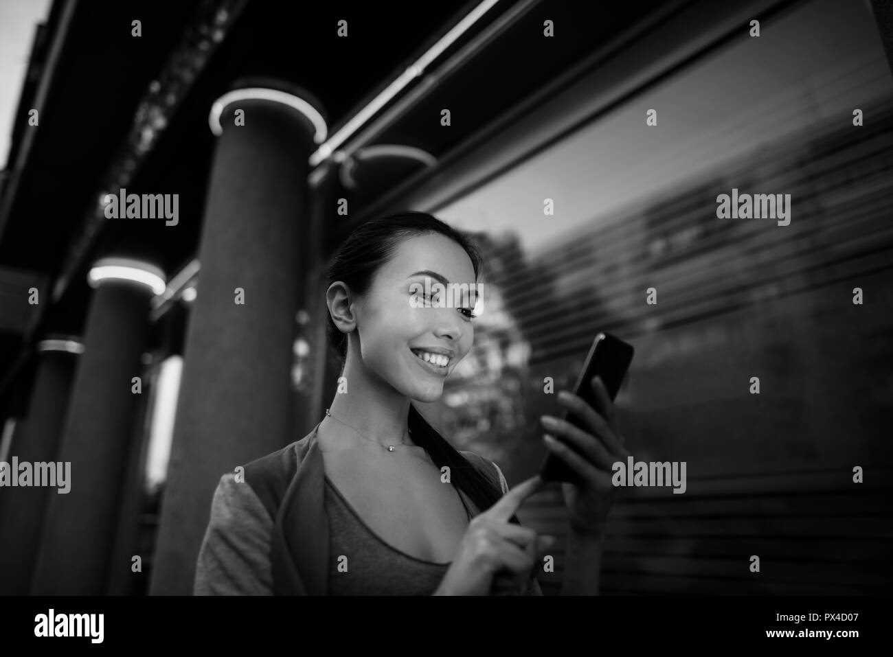 Black and white image of an asian woman using an application in her smart phone to read email, send text message, chat, browse or shop online Stock Photo