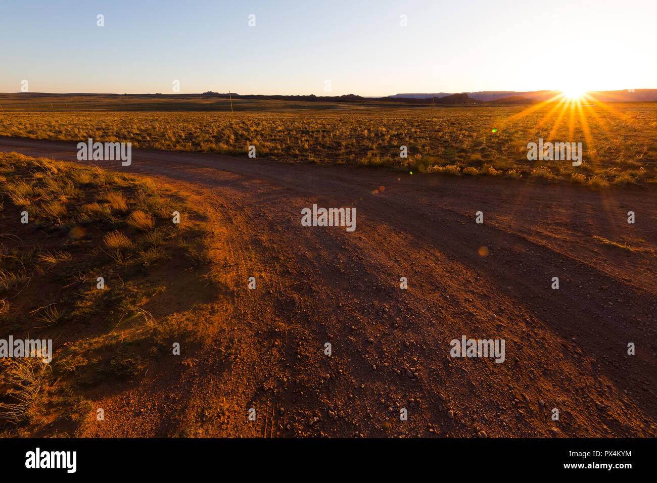 Shash Dine Navajo campsite, AZ, USA. The sun sets over a curve in a dirt track in the desert. Stock Photo