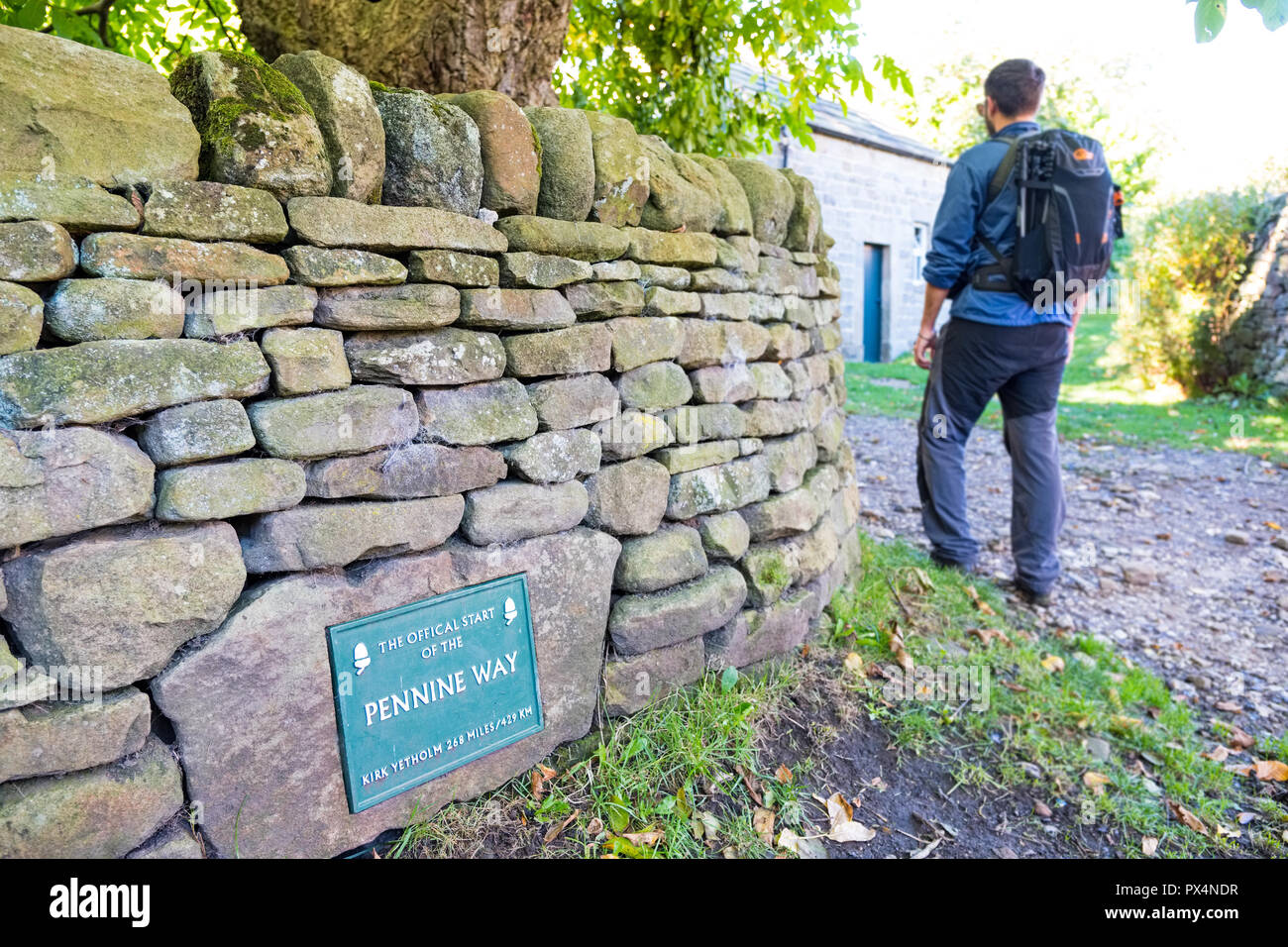 Young man walking past the plaque marking the start of the Pennine Way, Edale, Peak District National Park Stock Photo
