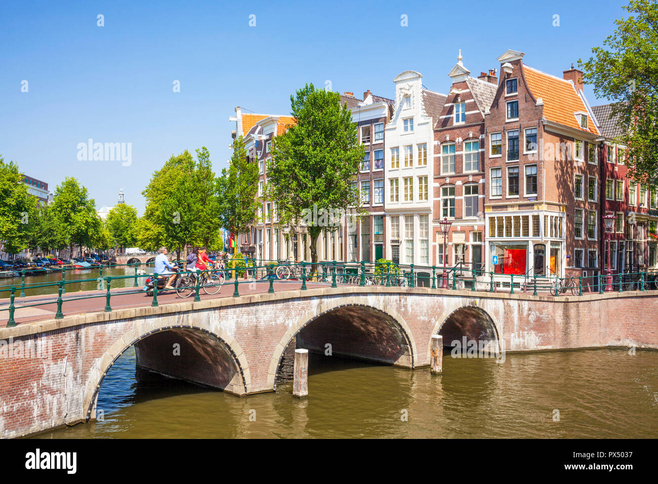 Amsterdam People on bicycles cross the bridge over the Keizergracht canal at its junction with Leilesgracht Amsterdam Netherlands Holland EU Europe Stock Photo