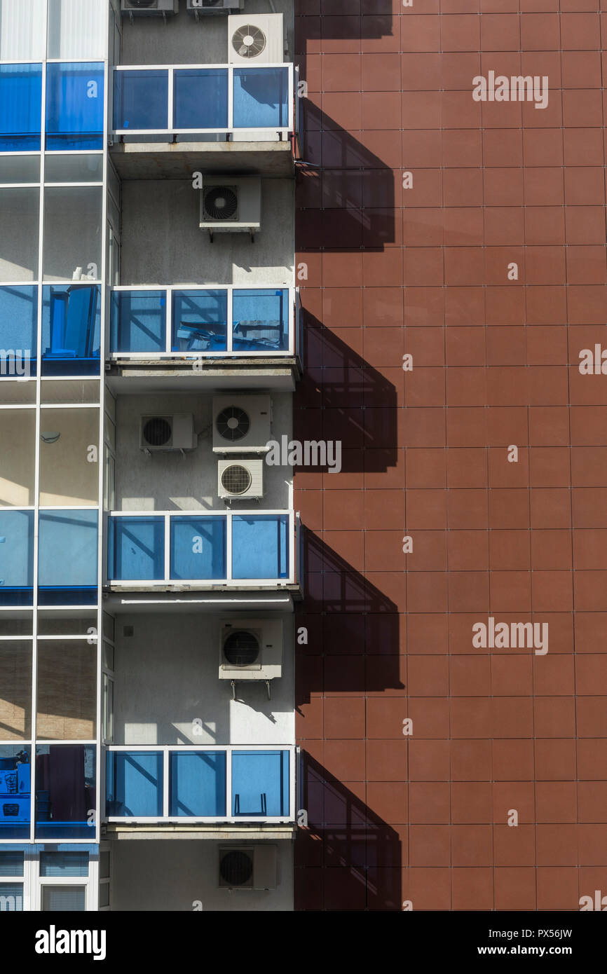 A building with brown tiles and glass balconies with air conditioning
