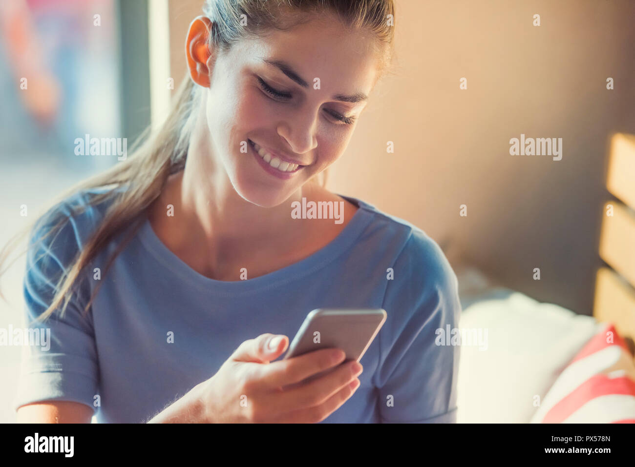 beautiful young woman is using an app in her cellphone device to receive a text message Stock Photo