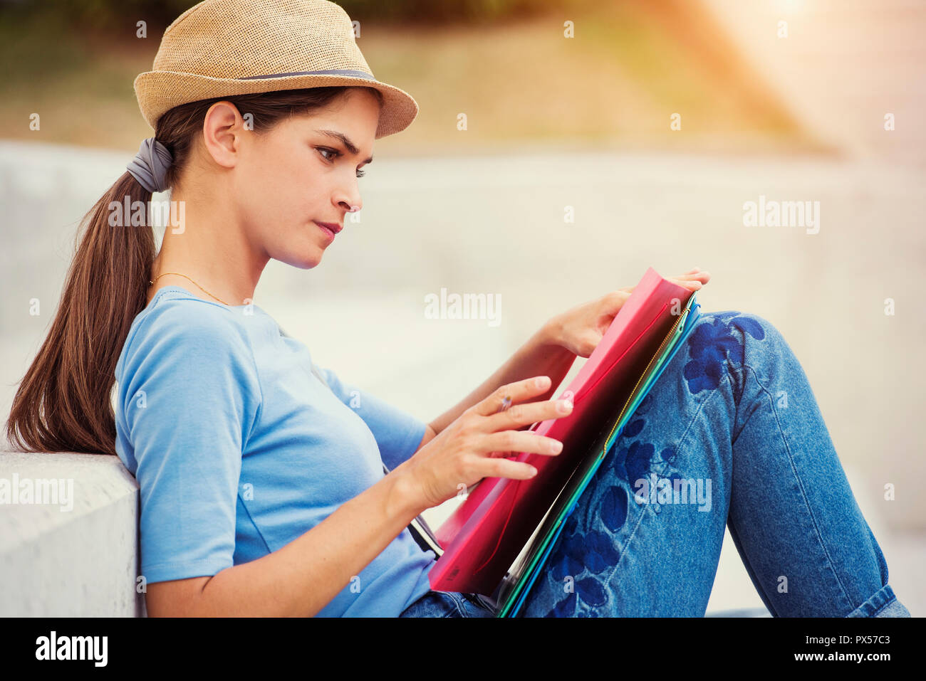 young woman college student is sitting in outdoor city park studying Stock Photo