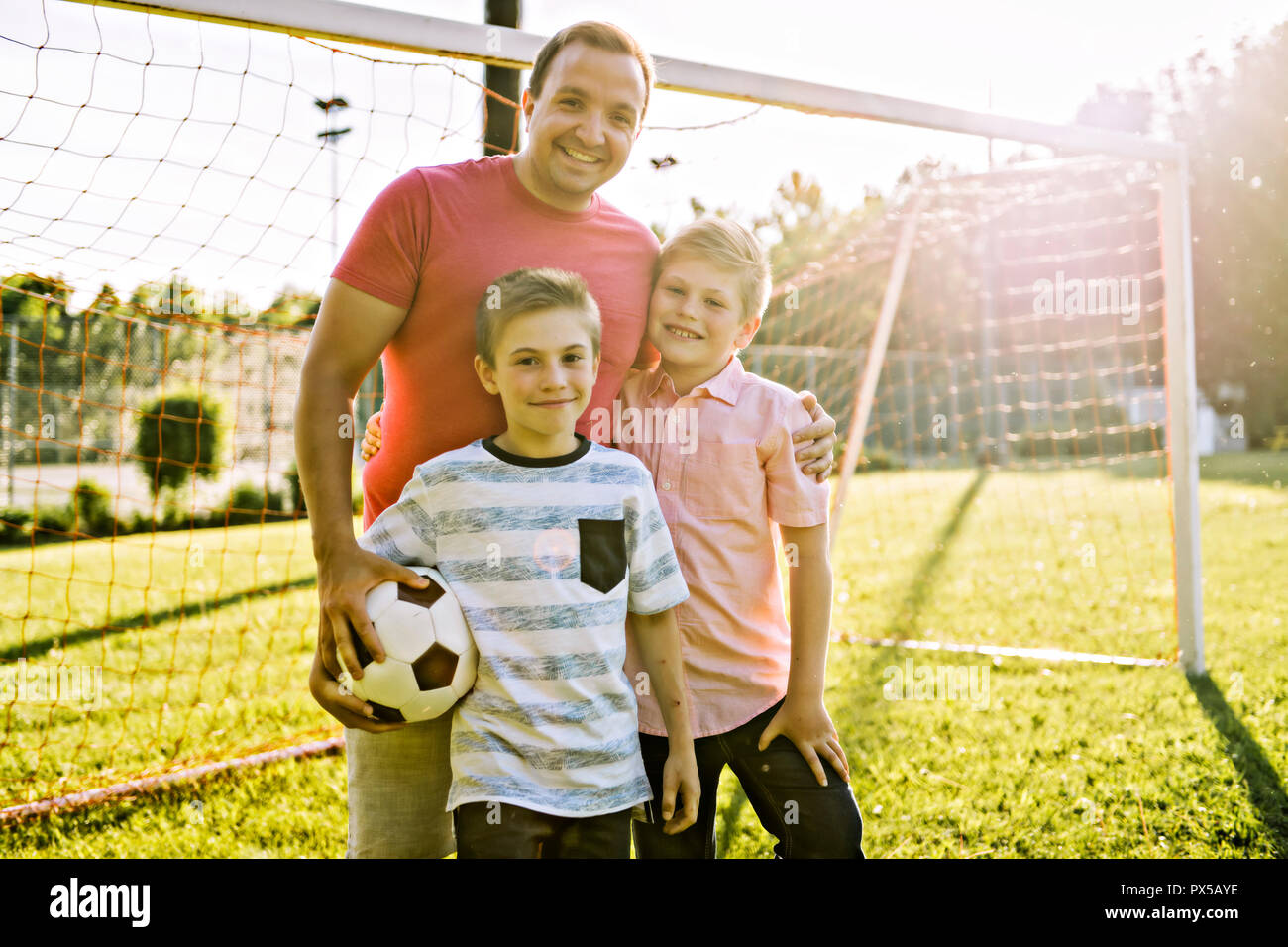man with child playing football outside on field Stock Photo