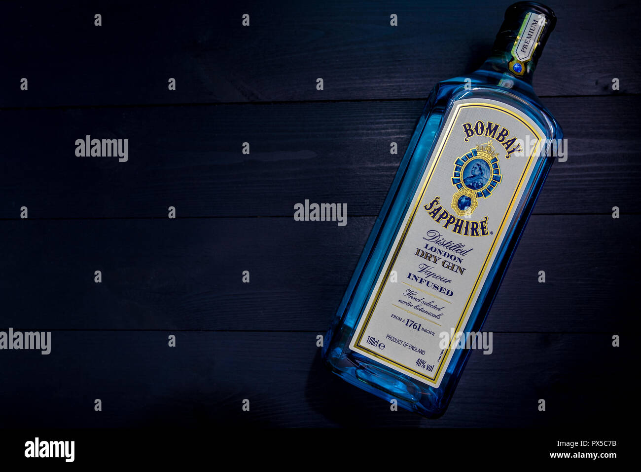 LONDON - OCTOBER 16, 2018: Bombay Sapphire Gin in blue glass bottle on dark wood background Stock Photo