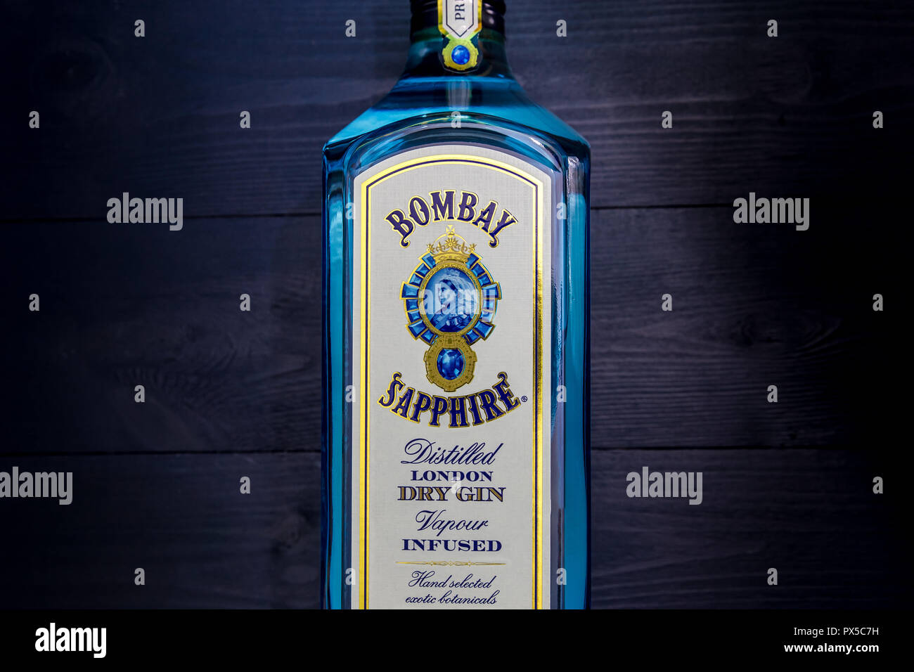 LONDON - OCTOBER 16, 2018: Bombay Sapphire Gin in blue glass bottle on dark wood background Stock Photo