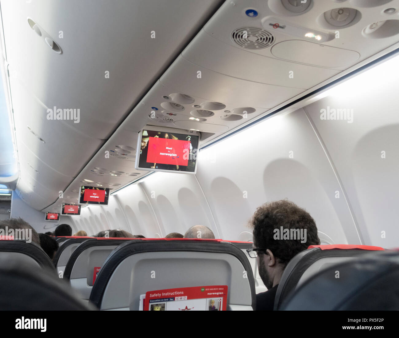 Drop down video screens on low cost Norwegian airlines flight. Stock Photo