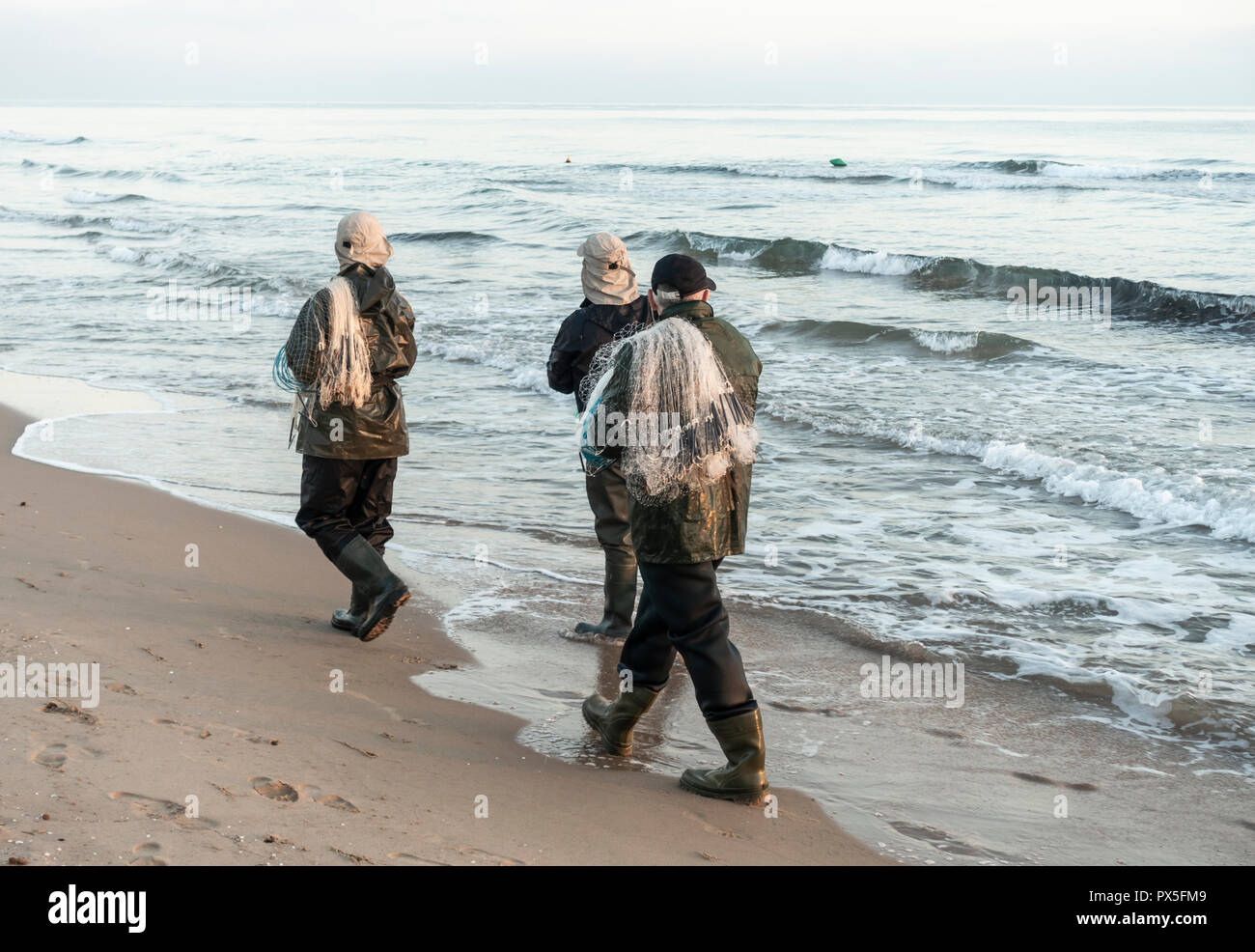 Spanish men fishing with nets from beach on the Costa del Azahar, south of Valencia Stock Photo