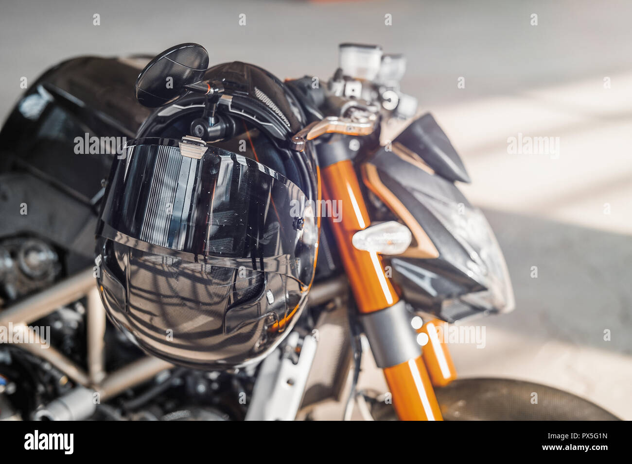 Close up of black glossy helmet at motorcycle. Urban background. Stock Photo