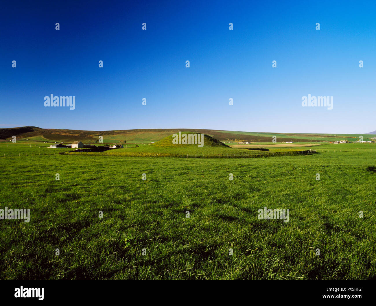 Looking west to Maes Howe Neolithic chambered cairn, Mainland, Orkney, Scotland, UK, showing the rear of the stone & clay mound standing on a raised c Stock Photo