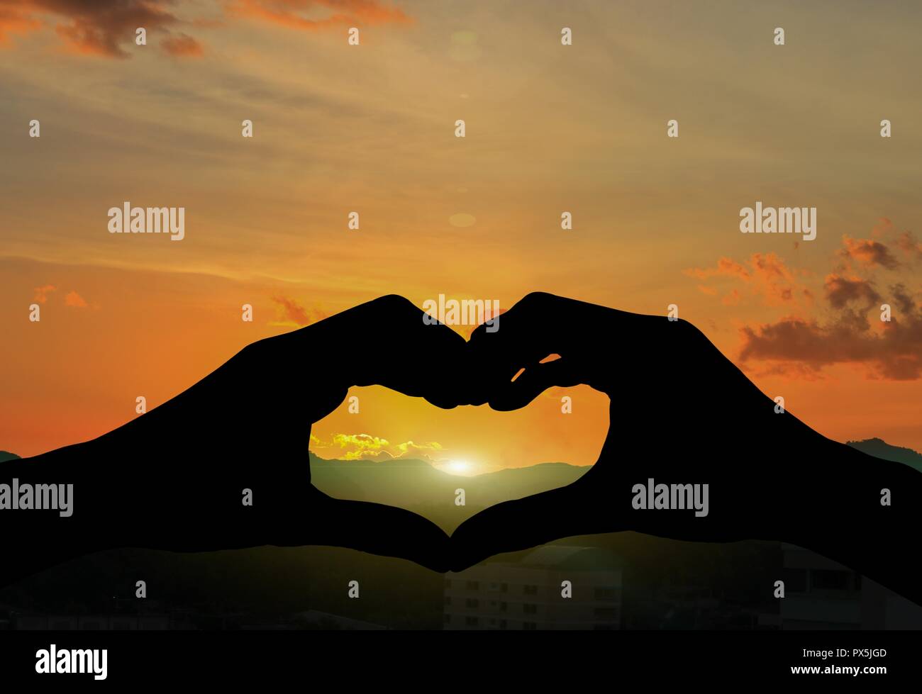 hand forming silhouette a heart shape with  sunset  light Stock Photo