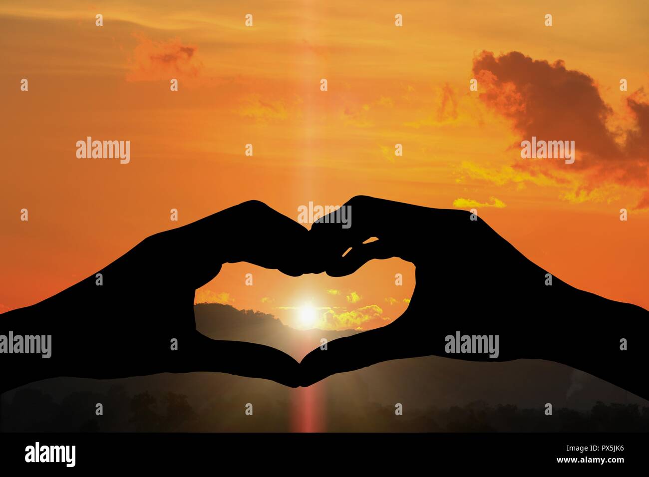 hand forming silhouette a heart shape with  sunset  light Stock Photo