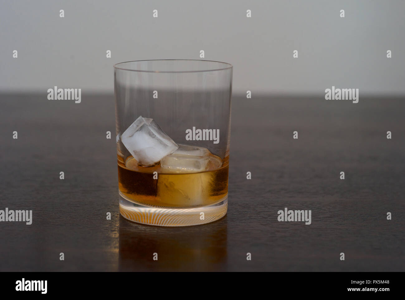 Whiskey, Bourbon, Scotch or Rum on the Rocks in an Elegant Tumbler on a Dark Wooden Table Stock Photo
