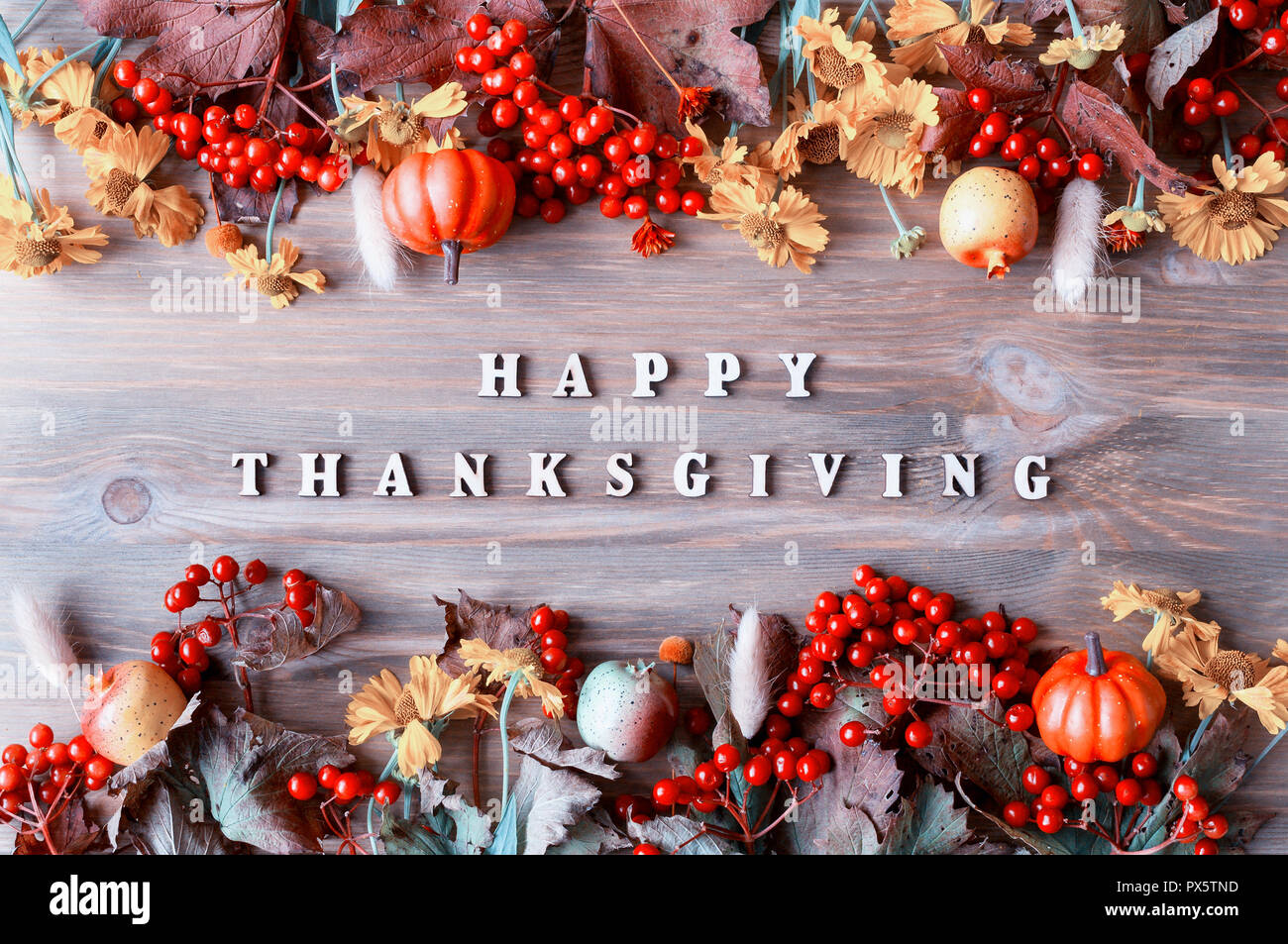 Happy Thanksgiving day holiday autumn background with Happy Thanksgiving letters, seasonal autumn nature berries, pumpkins, apples and flowers on the  Stock Photo