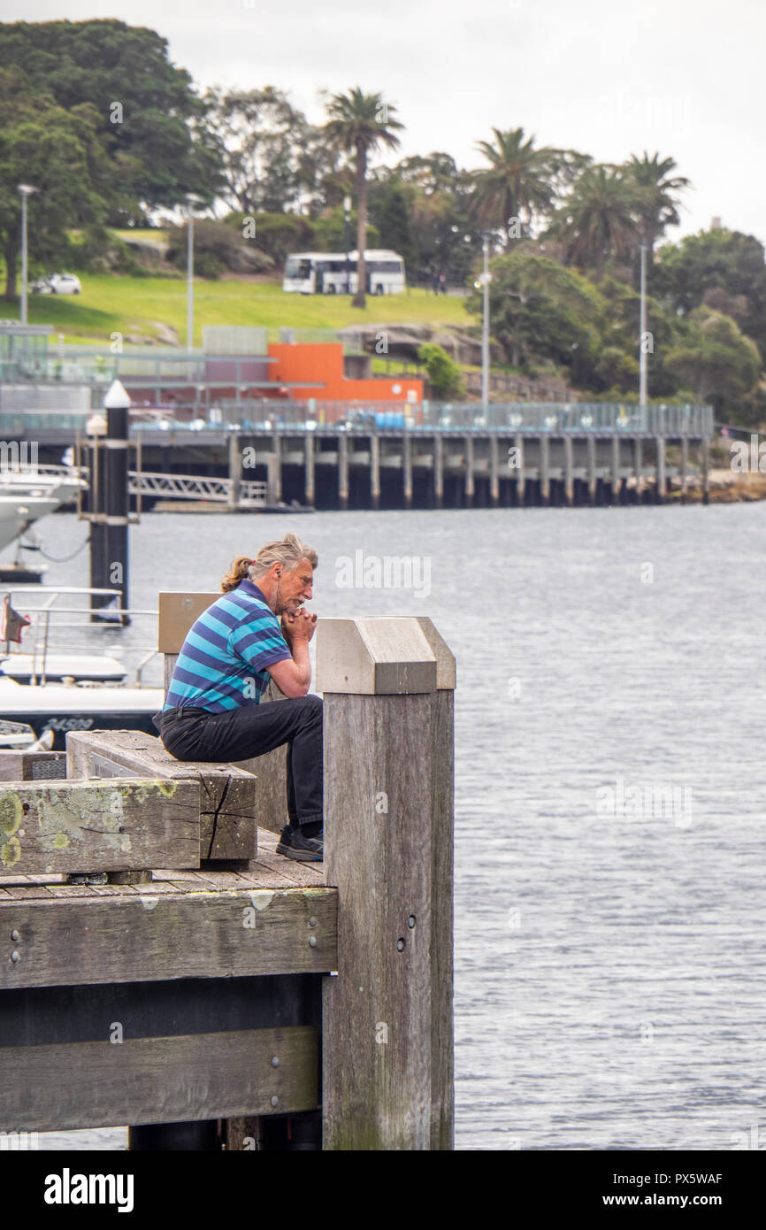 Miuddle age Caucasian man sitting at the end of a jetty Woolloomooloo Bay Sydney NSW Australia. Stock Photo