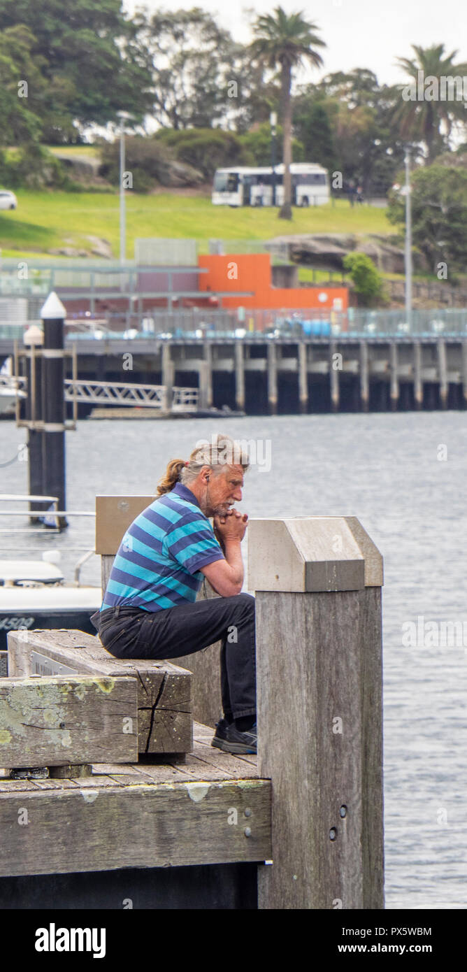 Miuddle age Caucasian man sitting at the end of a jetty Woolloomooloo Bay Sydney NSW Australia. Stock Photo