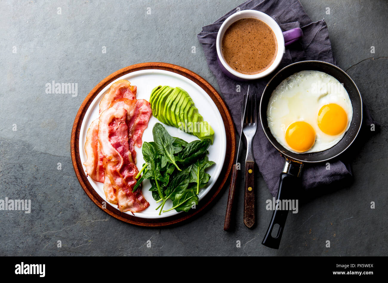 Ketogenic diet breakfast. fried egg, bacon and avocado, spinach and bulletproof coffee. Low carb high fat breakfast. Stock Photo