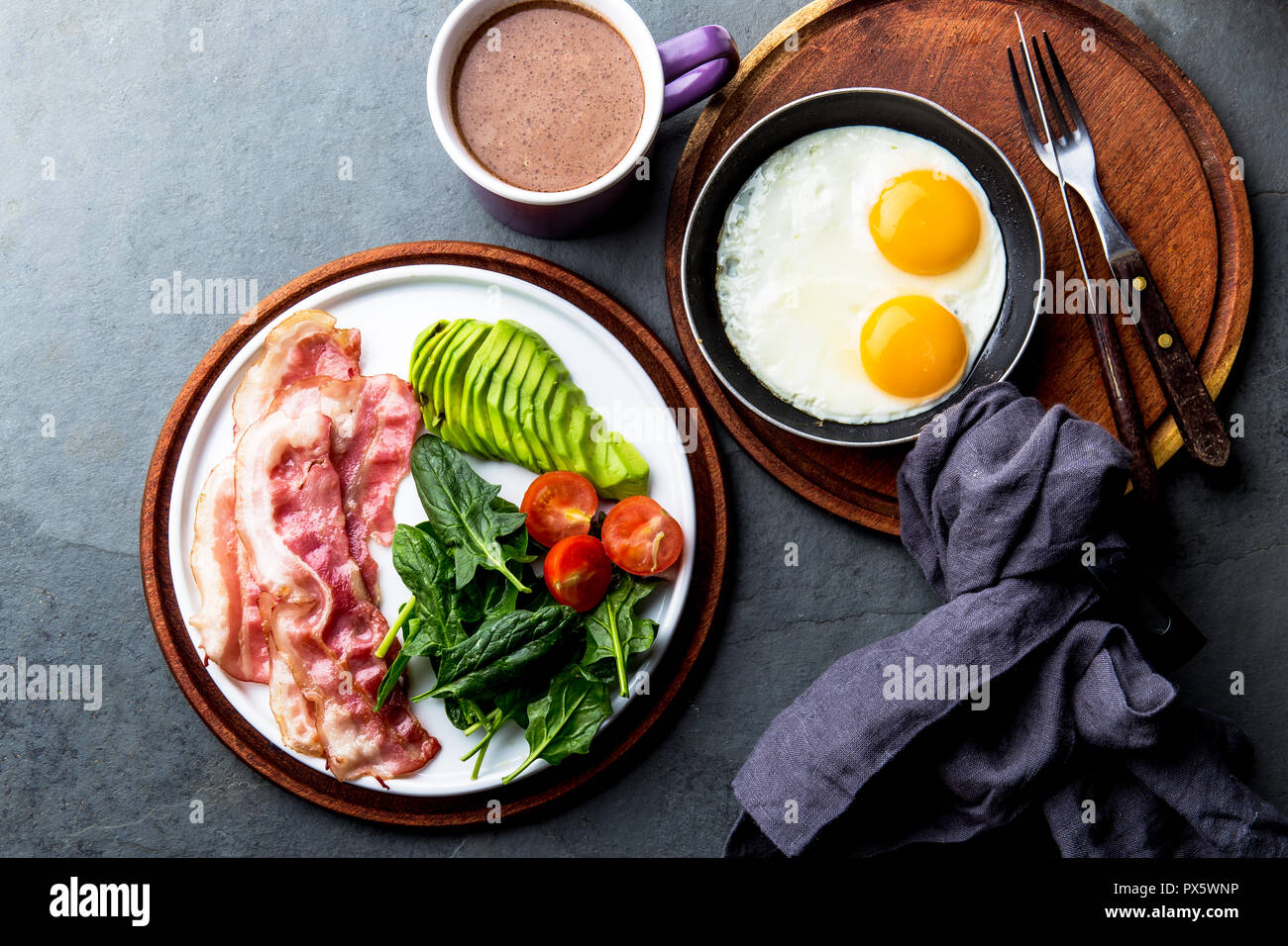 Ketogenic diet breakfast. fried egg, bacon and avocado, spinach and bulletproof coffee. Low carb high fat breakfast. Stock Photo