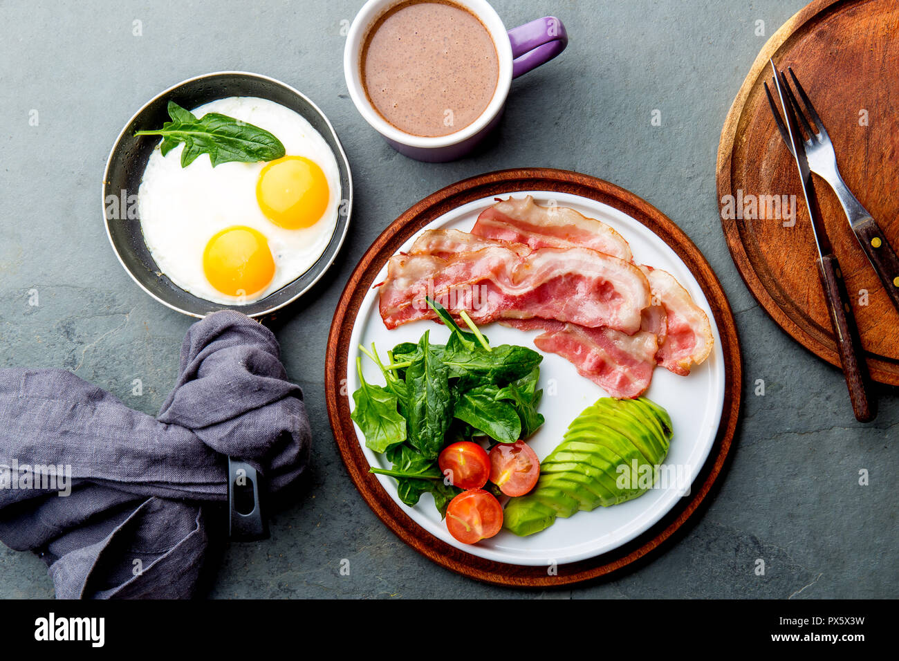 Ketogenic diet breakfast. fried egg, bacon and avocado, spinach and bulletproof coffee. Low carb high fat breakfast. Stock Photo
