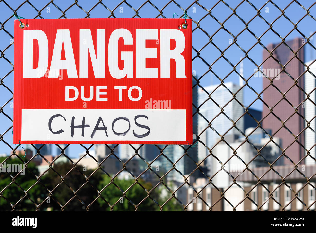 Sign danger due to chaos attached on the fence in the front of the town Stock Photo