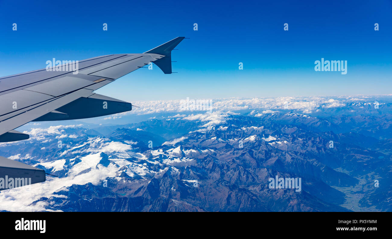 Mountains with snow and blue sky. Aerial view out of a plane window ...