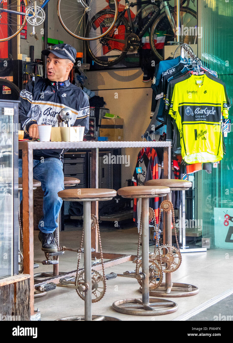 Man having a coffee in a cafe bicycle shop with bar stools with pedals