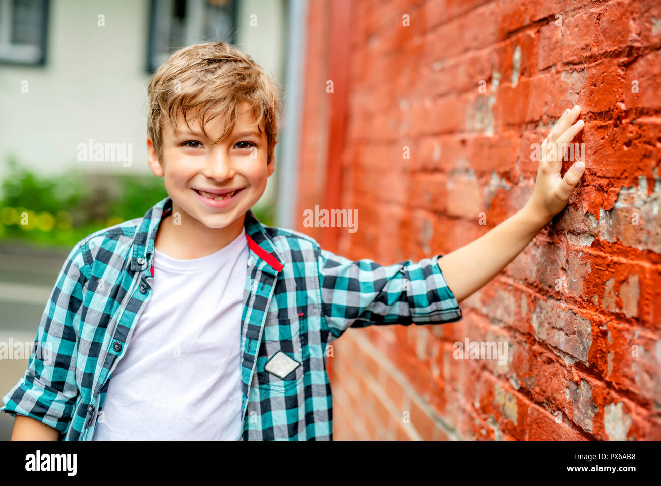 A adorable cute boy staing near a red brick wall Stock Photo - Alamy