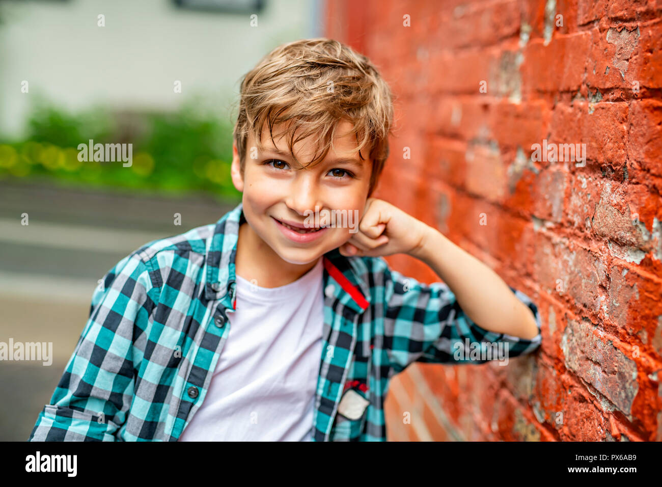 A adorable cute boy staing near a red brick wall Stock Photo - Alamy