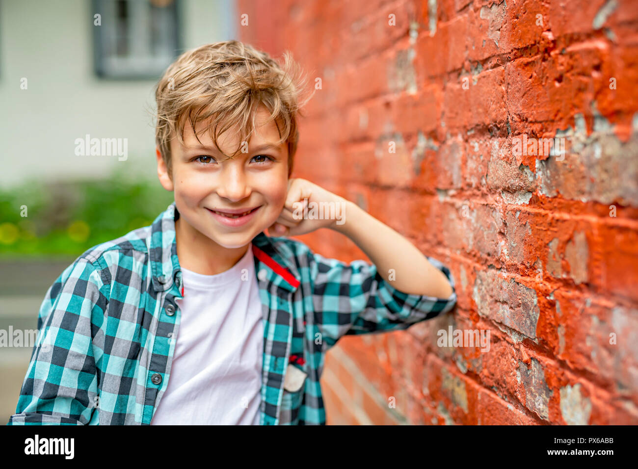 A adorable cute boy staing near a red brick wall Stock Photo - Alamy