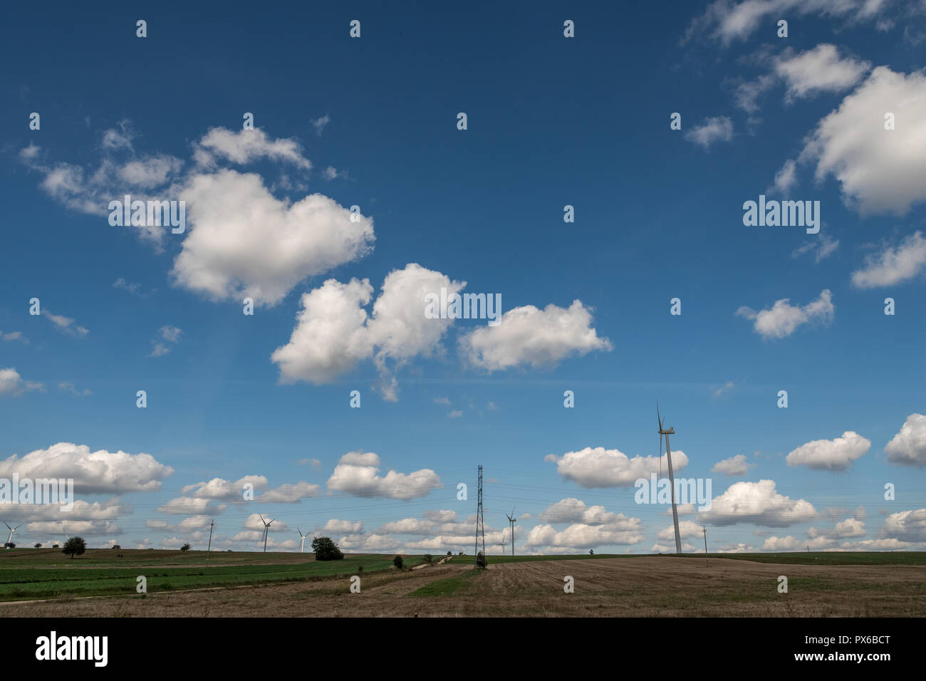 rural landscape with field and wind turbines over blue sky with cumulus ...
