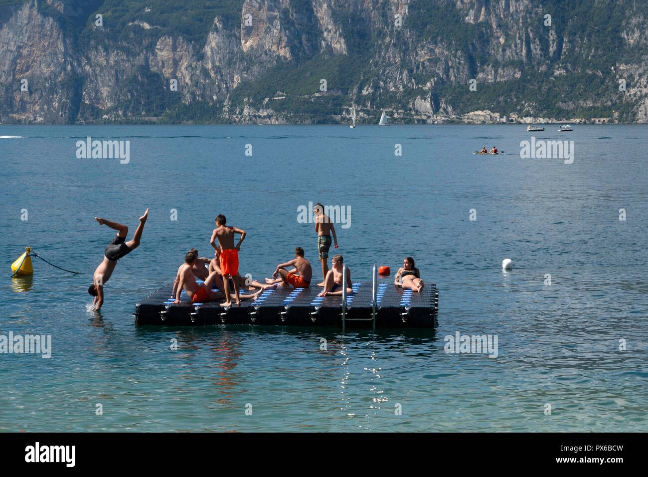 Italy, Garda Lake, Malcesine, 09.05.2018 Young people enjoying a sunny summer  afternoon on a bathing platform in Lake Garda Stock Photo