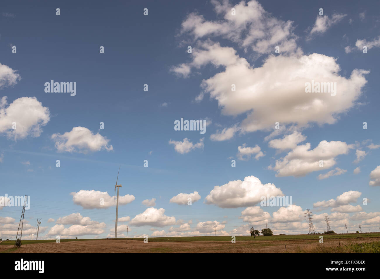rural landscape with field and wind turbines over blue sky with cumulus ...