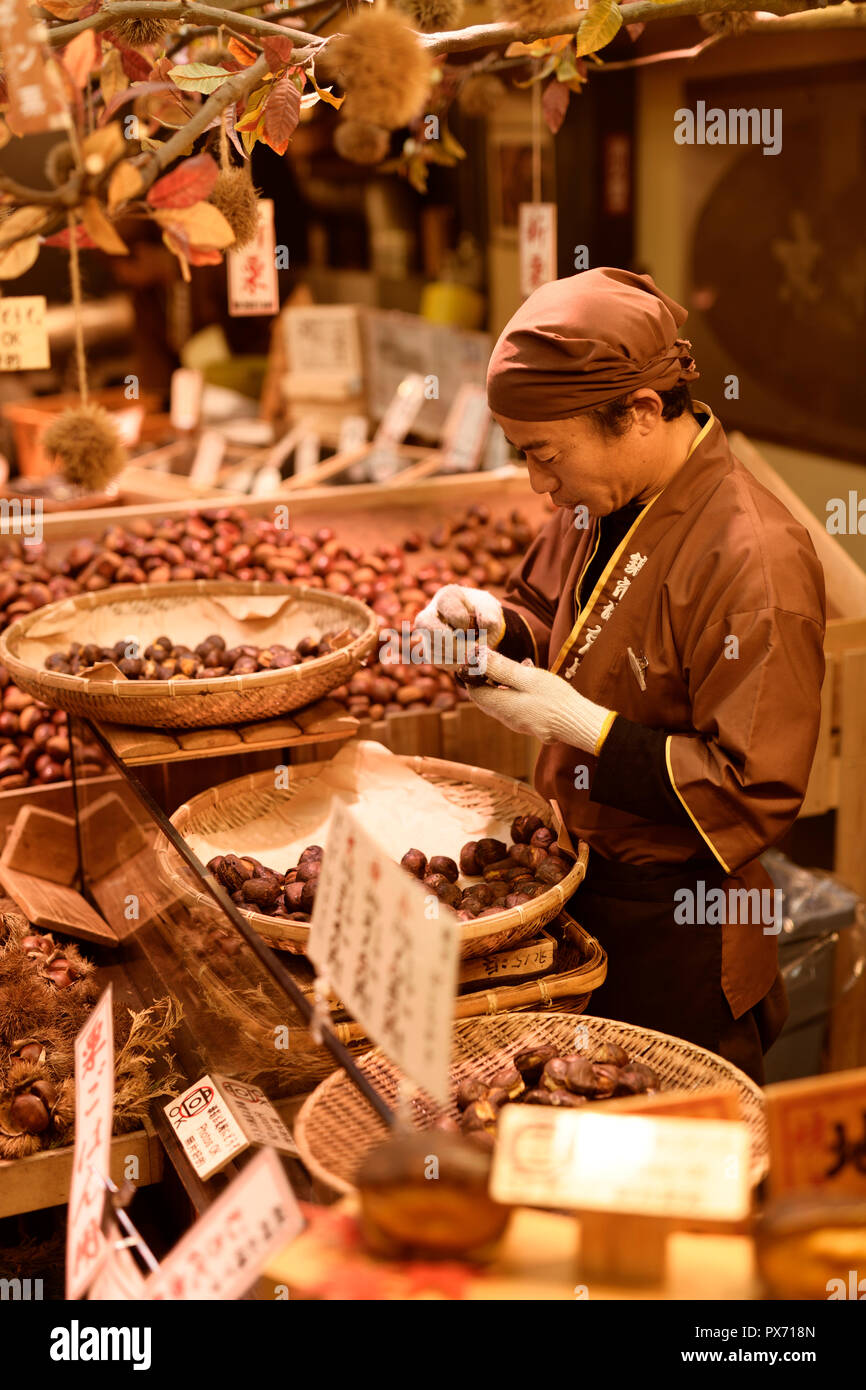 Japanese food vendor sorting Yakikuri, roasted chestnuts, at Nishiki food market shop stall in Kyoto, Japan 2017 Stock Photo
