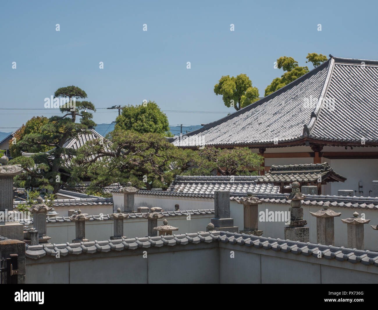Temple tile roof,   and cemetery wall with tile top, and memorial grave markers, Kagawa, Japan Stock Photo