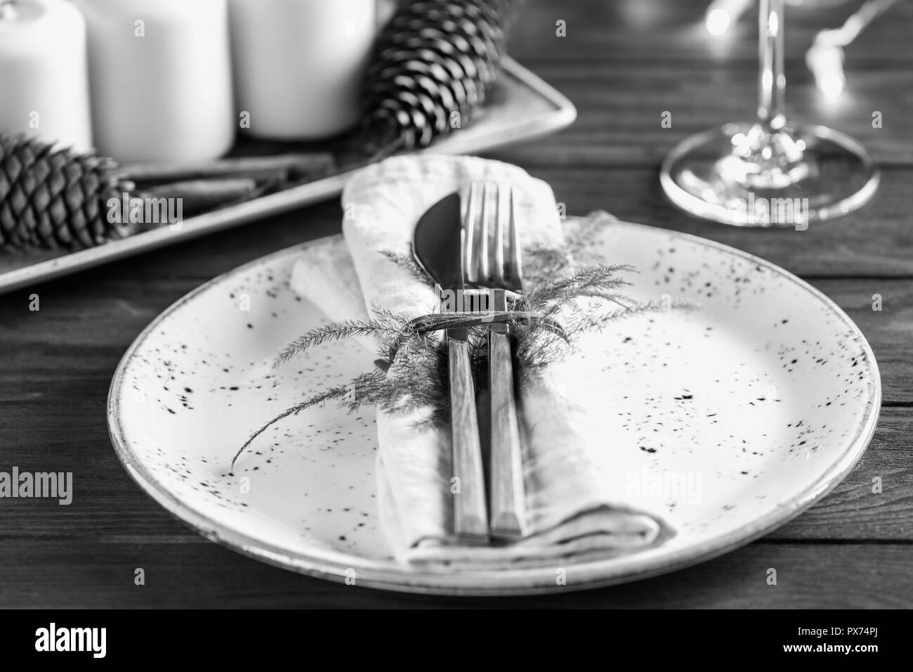 Decorated table setting among white candles and winter decor. The concept of a festive dinner. Black and white photography. Stock Photo