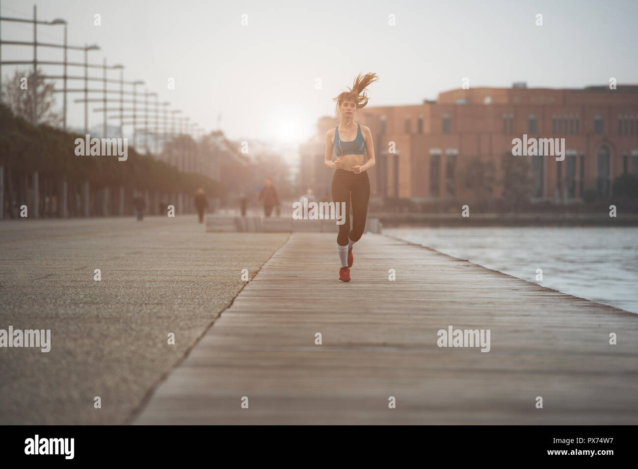 a woman jogging by the seaside in urban city environment Stock Photo