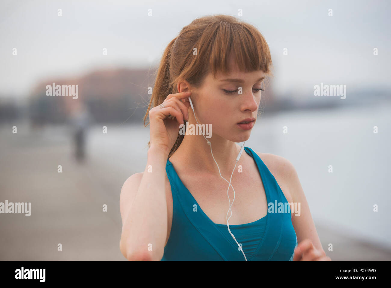 a woman athlete, running by the city seaside, putting on her earphones Stock Photo