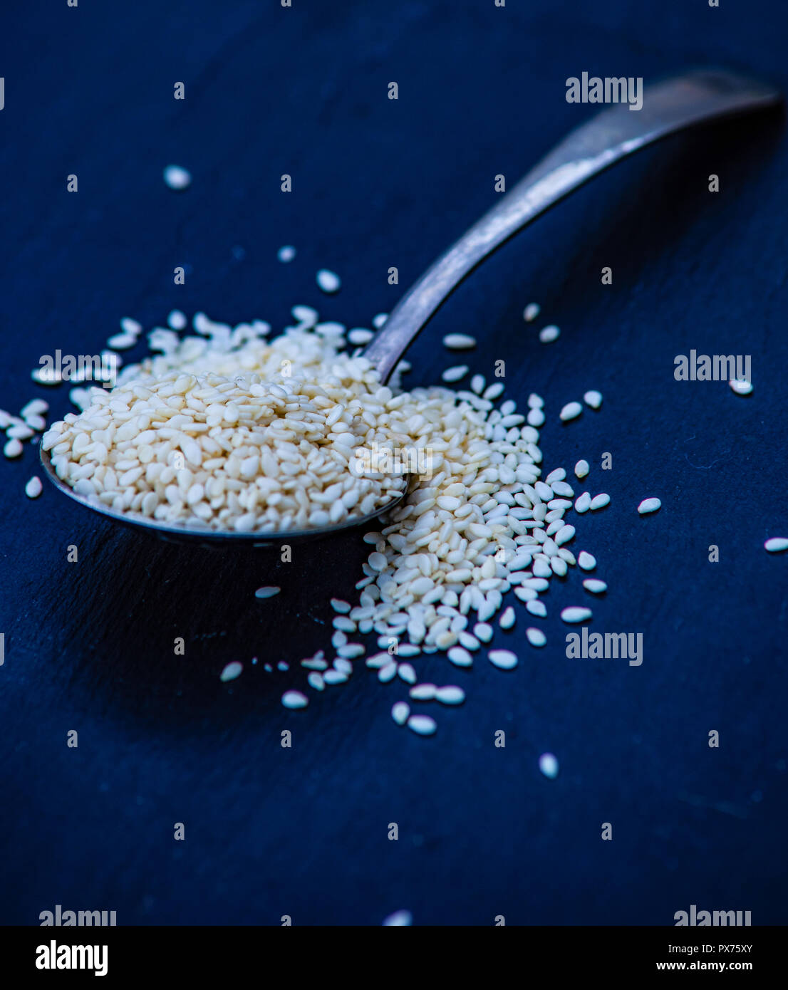 Organic superfood ingredient sesame seeds on black background with copy